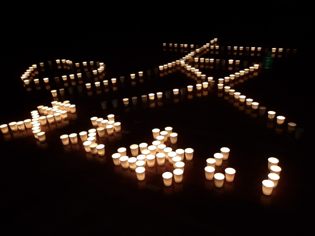 自然学校先の体育館で、ろうそくでつくった5年生の学年目標「支え合い」を表現した写真