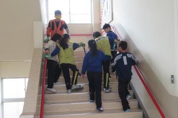 3年生が高齢者疑似体験で校舎内の階段を昇降している様子
