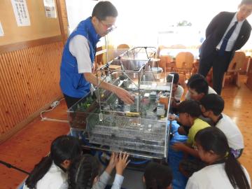 3年生が模型を見ながら洪水が起こる仕組みを聞いている様子