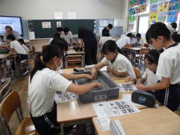 教室の勉強机をグループで近づけ、そのグループ数名の生徒で土器のかけらを触っています