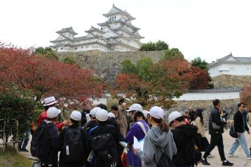 6年生が三の丸広場でしろまる会のガイドさんに姫路城の説明を受けている様子