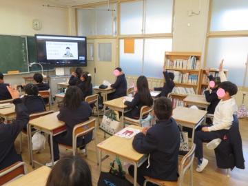 教室で席に座った3年生がテレビ画面に映る先生クイズに答えるようす