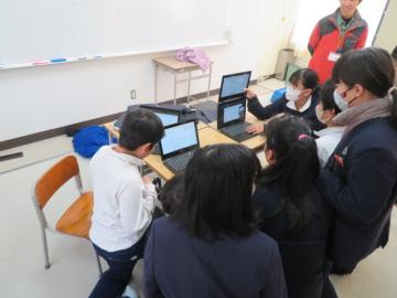 教室の机にオンライン用のパソコンを置き、画面に向かって放送委員会の生徒たちが並んでいる後ろから撮影したようす