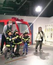 園児が消防服を着て、放水訓練を体験している様子