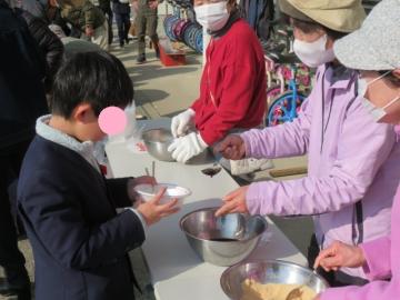 校庭でおもちのトッピングを選ぶ3年生の別の児童たちの様子