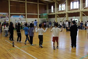 5年生が体育館でリーダーと一緒に踊っている様子