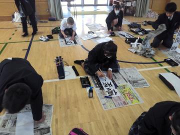 2026年の抱負を体育館の床に置かれた書に書く生徒たちの様子