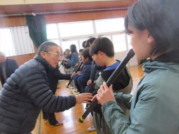体育館で講師から教わり尺八の体験をする児童たちの様子