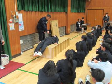 体育館で避難場所で使われる段ボールベッドの使用体験をする受講者の様子