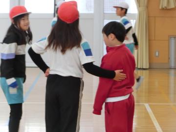 体育館で、大塩小学校の子が居住地交流の子の肩に手を添えて一緒に遊ぼうと声をかけているところ