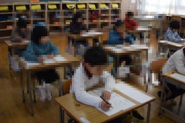 教室内で着席しペンで書初めをする児童たちの様子