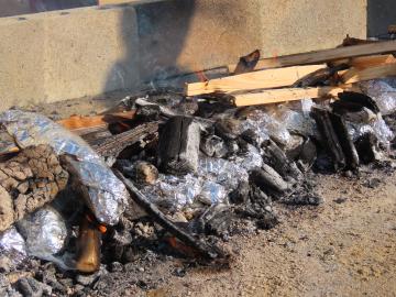 校庭で子供たちが包んだ芋を炭火で焼く様子