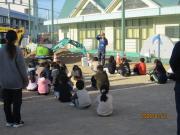 校庭での避難訓練で、講師の話を聞く児童たちの様子