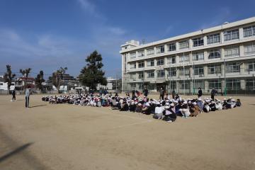 校庭に整列して座る全校生徒の全体写真