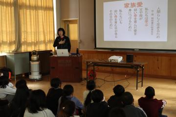 防災についてヴィクトリーナ姫路の通訳　阿部美奈子さんが5，6年生に体育館で話している写真