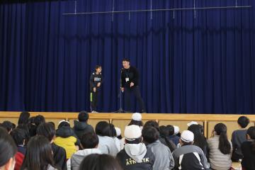 M-1グランプリで先生と5年生コンビが体育館の壇上で漫才している写真