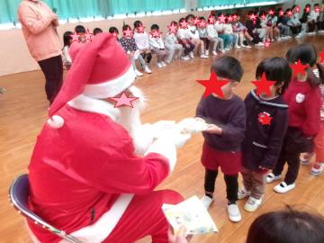 室内で3歳児がサンタさんにプレゼントをもらっている様子