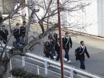 午後から登校する生徒が道路の端を歩いている様子