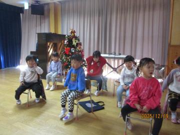 室内で3歳児がクリスマス会に参加している様子