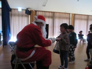 室内でサンタさんにプレゼントをもらう園児たちの様子