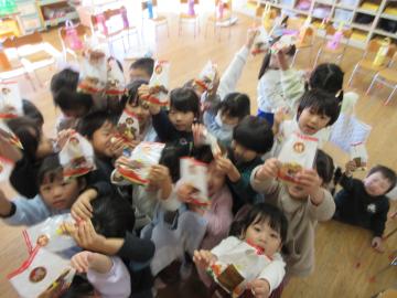 室内でサンタさんからのクッキーのプレゼントに喜んでいる園児たちの様子