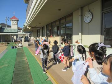 園庭で空に飛んで行ったサンタさんに手を振っている園児たちの様子