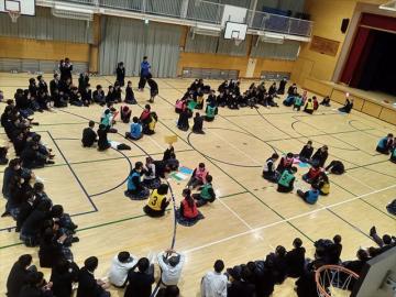 体育館で札を取り合う代表生徒と周りで応援する生徒たちの様子