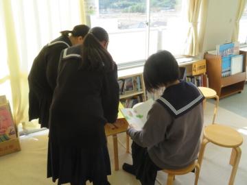 室内で大型絵本を手に取り読み聞かせの練習をする鹿谷中学校3年生の生徒たちの様子