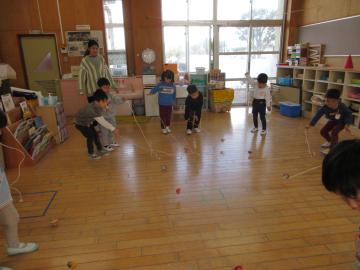 室内で木芯コマで遊んでいる4歳児たちの様子