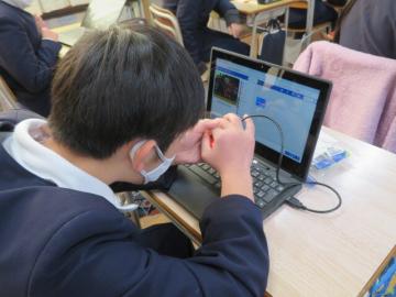 教室内でマイクロビットを手で覆い暗くしてみる6年生の様子