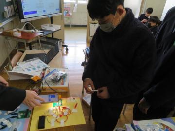 教室内でマイクロビットを回路につなぎ確かめる6年生の様子