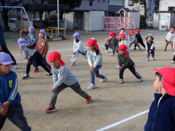 運動場で準備運動をする幼児たち