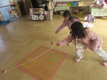 教室でこま回しをする幼児