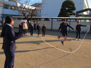 校庭において、たてわり班で長縄とびをする子どもたち