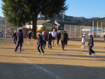 校庭において、たてわり班でおにごっこをする子どもたち