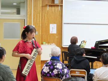 会場内で鍵盤ハーモニカの楽器本体を見せながら演奏してくださっている様子
