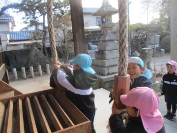 神社の鐘を子供が二人で持って嬉しそうに鳴らす様子