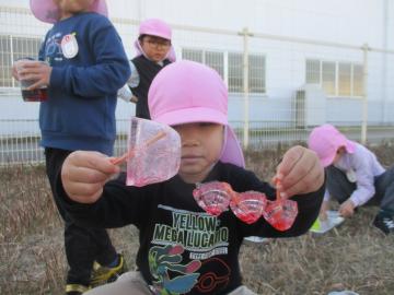 絵の具を混ぜて作った赤い氷を見せる子供