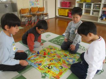 4人ですごろくを囲んで遊んでいる様子