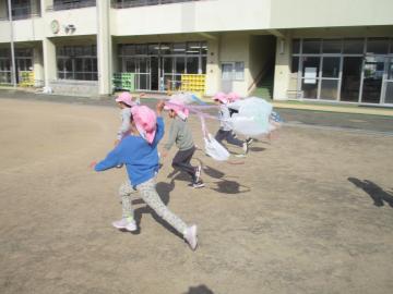 ナイロン袋で作った凧をもって走る子供たち