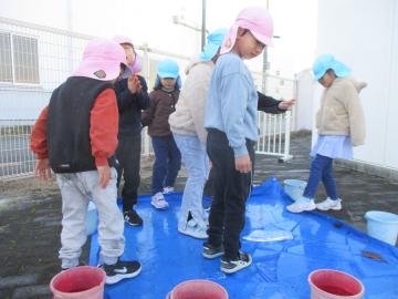 ブルーシートに氷が張り、氷の上を歩く子どもたち