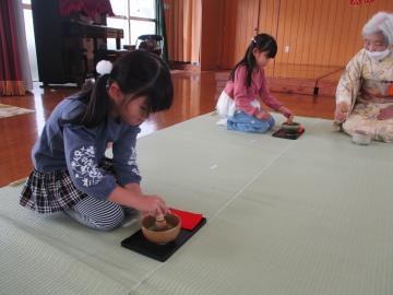 室内で茶筅を使いお茶をたてる子供
