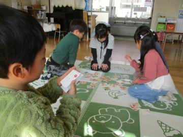 カルタを読む子供と絵札をとろうとする子供たち