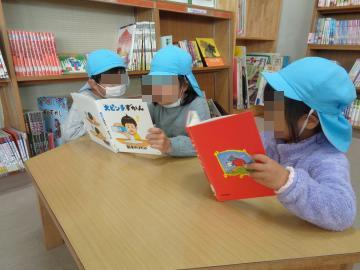 園児が図書室で友達と一緒に本を見ている