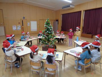 教室で輪にしたテーブルに座った園児が昼食を食べている