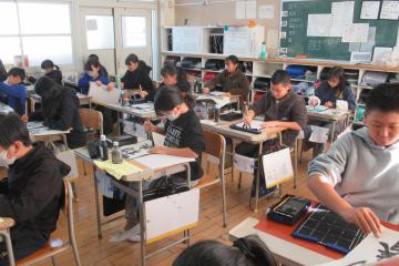 教室で5年生が書き初めに取り組んでいる様子