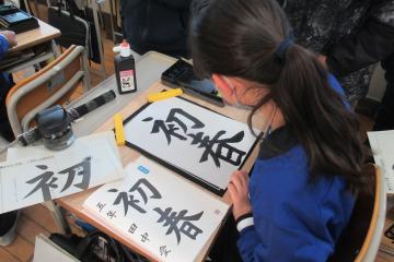 児童が机に向かって書いた完成した書き初め作品の様子