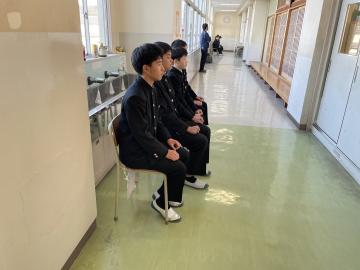 面接練習をする生徒が、廊下で椅子に座って自分の順番を待っているようす