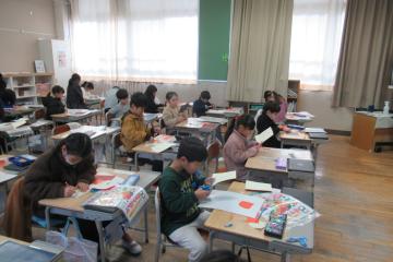 教室で1年生がはさみを使って色紙を切り取っている様子