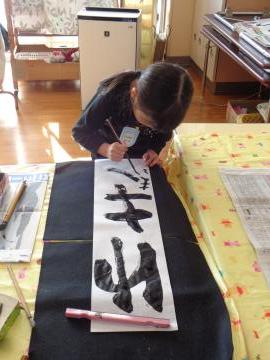 遊戯室で幼児が習字に挑戦している様子